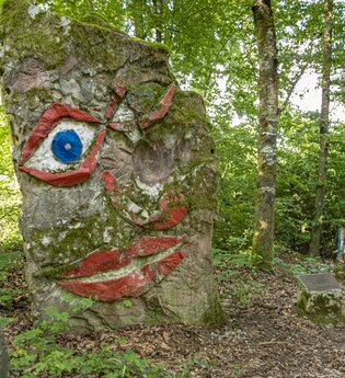 Ein großer Baumstumpf mit einem aufgemalten Gesicht im Wald. Seckach im Odenwald. | © Touristikgemeinschaft Odenwald e.V.