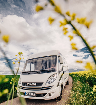 Ein weisses Wohnmobil auf einer Straße. Links ist ein grünes Feld auf der rechten Seite ein gelbes Rapsfeld. Odenwald. | © Touristikgemeinschaft Odenwald e.V.