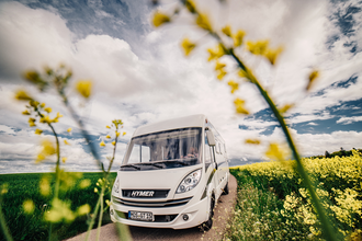 Ein weisses Wohnmobil auf einer Straße. Links ist ein grünes Feld auf der rechten Seite ein gelbes Rapsfeld. Odenwald. | © Touristikgemeinschaft Odenwald e.V.