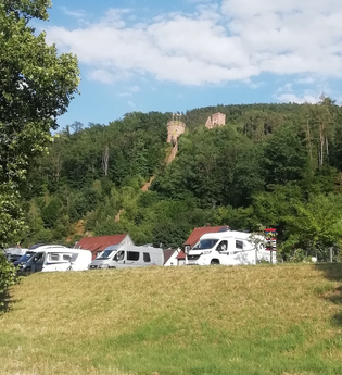 Blick auf den Wohnmobilstellplatz am Stadteingang Süd in Freudenberg am Main. Im Hintergrund ist von Wald umgeben die Freudenburg zu sehen. | © Liebliches Taubertal