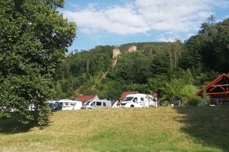 Blick auf den Wohnmobilstellplatz am Stadteingang Süd in Freudenberg am Main. Im Hintergrund ist von Wald umgeben die Freudenburg zu sehen. | © Liebliches Taubertal