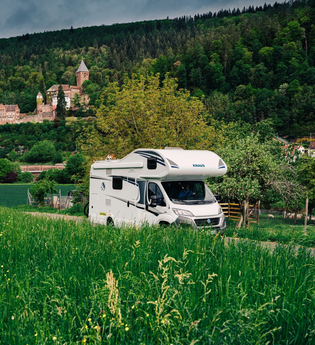 Im Vordergrund ist eine grüne Wiese mit einem Wohnmobil zu sehen. Im Hintergrund ein Schloss. Es handelt sich um das Schloss Zwingenberg am Neckar im Odenwald. | © Touristikgemeinschaft Odenwald