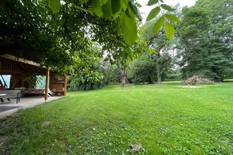 Blick auf den Wohnmobilstellplatz auf dem Ferienbauernhof Schamman in Neubronn. Es ist eine von Bäumen umgebene Wiese mit einer Pergola zu sehen. | © Touristinfo Weikersheim