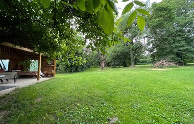 Blick auf den Wohnmobilstellplatz auf dem Ferienbauernhof Schammann in Neubronn. Es ist eine von Bäumen umrandete Wiese und eine Pergola zu sehen. | © Touristinfo Weikersheim
