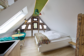 Schlafzimmer mit Doppelbett und einem kleinen Tisch mit zwei bequemen türkisfarbenen Stühlen | © Neckar-Zaber-Tourismus e.V.