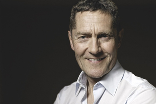 Porträt eines lächelnden Mannes in einem weißen Hemd vor dunklem Hintergrund. | © Kulturstiftung Hohenlohe