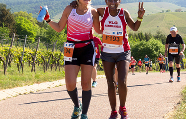 Zwei Läuferinnen laufen einen Berg in den Weinbergen hinauf und lächeln in die Kamera | © Heilbronn Marketing GmbH