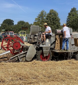zwei personen auf einer Dreschmaschine uaf dem Feld