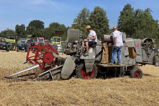 zwei personen auf einer Dreschmaschine uaf dem Feld