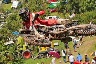 Ein Motorradfahrer in roter Kleidung mitten im Sprung, im Hintergrund Zuschauer | © Rainer Kengeter