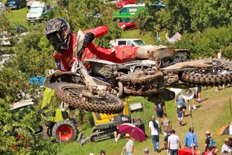 Ein Motorradfahrer in roter Kleidung mitten im Sprung, im Hintergrund Zuschauer | © Rainer Kengeter