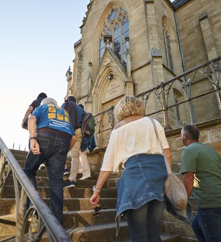 Eine Führung auf den Treppenstufen vor der evangelischen Kirche | © Touristikgemeinschaft HeilbronnerLand I Stefan Leitner Photography