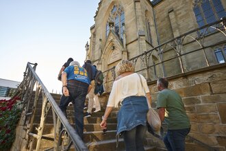 Eine Führung auf den Treppenstufen vor der evangelischen Kirche | © Touristikgemeinschaft HeilbronnerLand I Stefan Leitner Photography