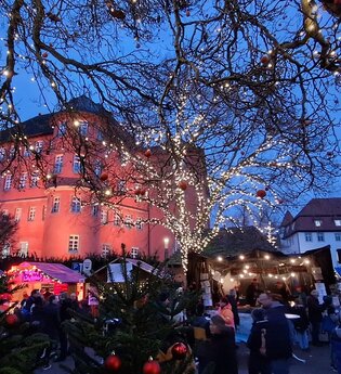 Blick auf den festlich geschmückten Weihnachtsmarkt in Künzelsau mit Schloss Bartenau im Hintergrund