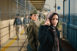 Eine Frau in Uniform und eine Frau mit Schal an einem Bahnsteig