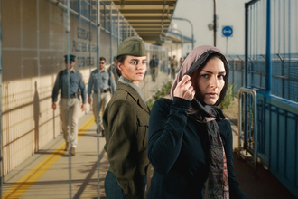 Eine Frau in Uniform und eine Frau mit Schal an einem Bahnsteig