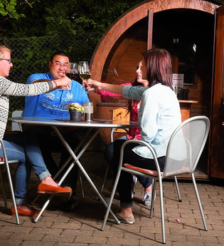 Drei Personen sitzen vor einem Weinfass und stoßen an | © Touristikgemeinschaft Hohenlohe e. V. | Winzerstube Lösch