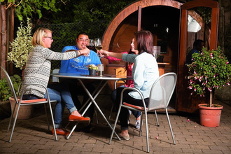 Drei Personen sitzen vor einem Weinfass und stoßen an | © Touristikgemeinschaft Hohenlohe e. V. | Winzerstube Lösch