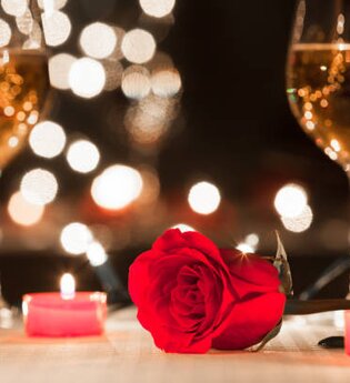 Ein Tisch mit zwei Glas Wein, Kerzen, einer Rose sowie Lichtern im Hintergrund | © Touristikgemeinschaft Hohenlohe e. V. | Michael Wendler, Hoftheater Öhringen