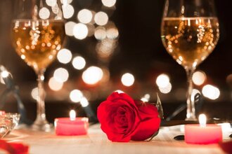 Ein Tisch mit zwei Glas Wein, Kerzen, einer Rose sowie Lichtern im Hintergrund | © Touristikgemeinschaft Hohenlohe e. V. | Michael Wendler, Hoftheater Öhringen