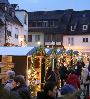 Blick auf den Weihnachtsmarkt mit geschmückten Weihnachtsbäumen und Weihnachtsbaumhütten