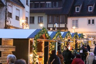 Blick auf den Weihnachtsmarkt mit geschmückten Weihnachtsbäumen und Weihnachtsbaumhütten