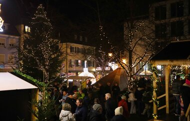 Blick auf den Weihnachtsmarkt mit geschmückten Weihnachtsbäumen und Weihnachtsbaumhütten