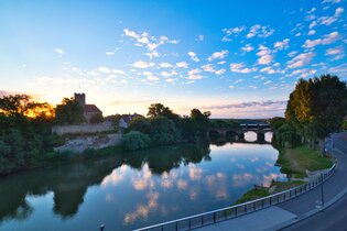 Blick über den Fluss zum Rathausburg in Lauffen am Neckar bei Sonnenuntergang.