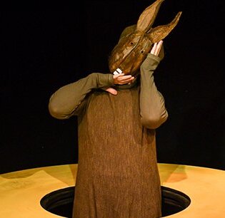 Eine Figur mit einer Hasenmaske steht in einem gelben Kreis.
