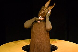 Eine Figur mit einer Hasenmaske steht in einem gelben Kreis.