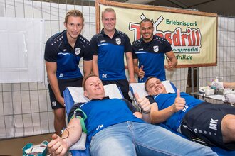 Zwei Männer liegen auf Liegen und spenden Blut, während drei weitere Männer daneben stehen und Daumen hoch zeigen. | © Erlebnispark Tripsdrill