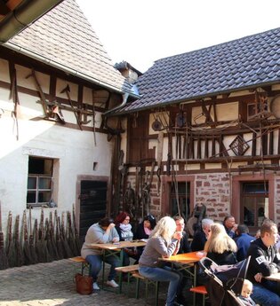 Leute sitzen an Bierbanken vor einem Fachwerkhaus | © Landratsamt Rhein-Neckar-Kreis