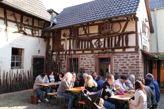 Leute sitzen an Bierbanken vor einem Fachwerkhaus | © Landratsamt Rhein-Neckar-Kreis