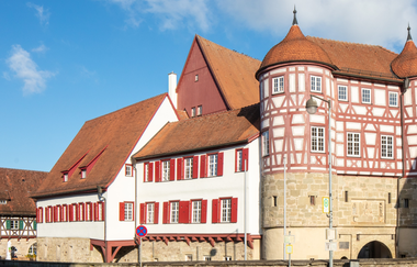 altes Schloss - rechts das Torhaus mit Sockelgeschoss aus hellem Sandstein und aufgesetztem roten Fachwerk mit weißen Gefachen, flankiert von zwei Rundtürmen. In der Bildmitte der Westflügel mit zwei aneinandergebauten, weiß verputzten Gebäudeteilen mit r | © Stadt Gaildorf