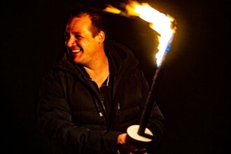 Lachender Mann mit Fackel bei Nacht