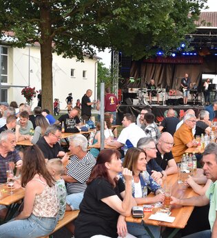Menschen sitzen beim Fest auf Bierbänken vor der Bühne | © Werner Stuber