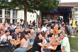 Menschen sitzen beim Fest auf Bierbänken vor der Bühne | © Werner Stuber
