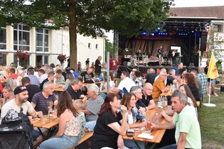 Menschen sitzen beim Fest auf Bierbänken vor der Bühne | © Werner Stuber