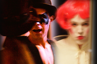 ein Künstler mit AugMaske und Hut. Ein Künstler mit roter Perücke