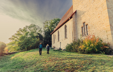 Bergkirche Heinsheim mit Wanderern in der Abendsonne. | © Touristikgemeinschaft Odenwald I Chris Frumolt