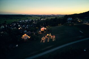 Luftaufnahme des Teilorts Goldbach, zu sehen ist eine Turmsilhouette aus Kerzen | © Julien Fertl