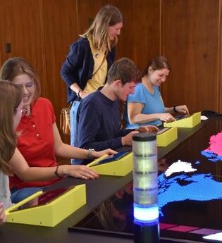 Einige Menschen sitzen am Spieletisch im Mark Twain Center. Es kann ein interaktives Strategiespiel gespielt werden.