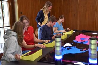 Einige Menschen sitzen am Spieletisch im Mark Twain Center. Es kann ein interaktives Strategiespiel gespielt werden.