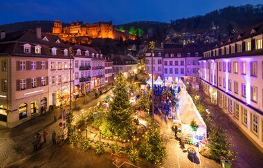 Winterwäldchen auf dem Kornmarkt mit weihnachtlichen Tannen und dem Heidelberger Schloss im Hintergrund. | © Heidelberg Marketing GmbH / Jan Becke