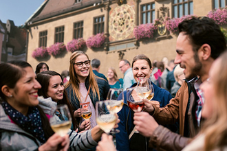 Fröhlich feiernde Gruppa an Gästen auf dem Marktplatz vor dem Rathaus. Alle haben ein Weinglas in der Hand und stoßen auf den schönen Abend auf dem Weindorf an. | © Heilbronn Marketing GmbH