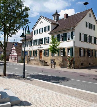 Außenansicht eines historischen Dorfhauses mit einer Dorfstraße im Vordergrund. | © Stadt Brackenheim