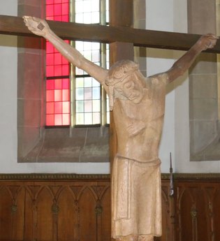 Kruzifix im Chor der Gaildorfer Stadtkirche, im Hintergrund rote Glasfenster | © Petra Natzkowski
