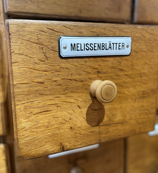 geöffnete Schublade eines Apothekerschranks mit der Aufschrift "Melissenblätter"