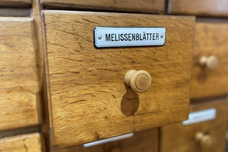 geöffnete Schublade eines Apothekerschranks mit der Aufschrift "Melissenblätter"