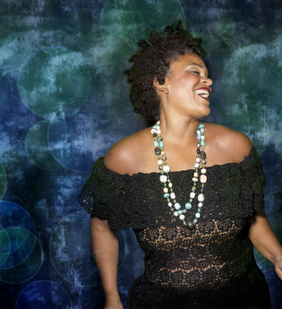 Frau in schwarzem Spitzenkleid vor blau-grünem Hintergrund. | © Jazzclub Schwäbisch Hall e.V.